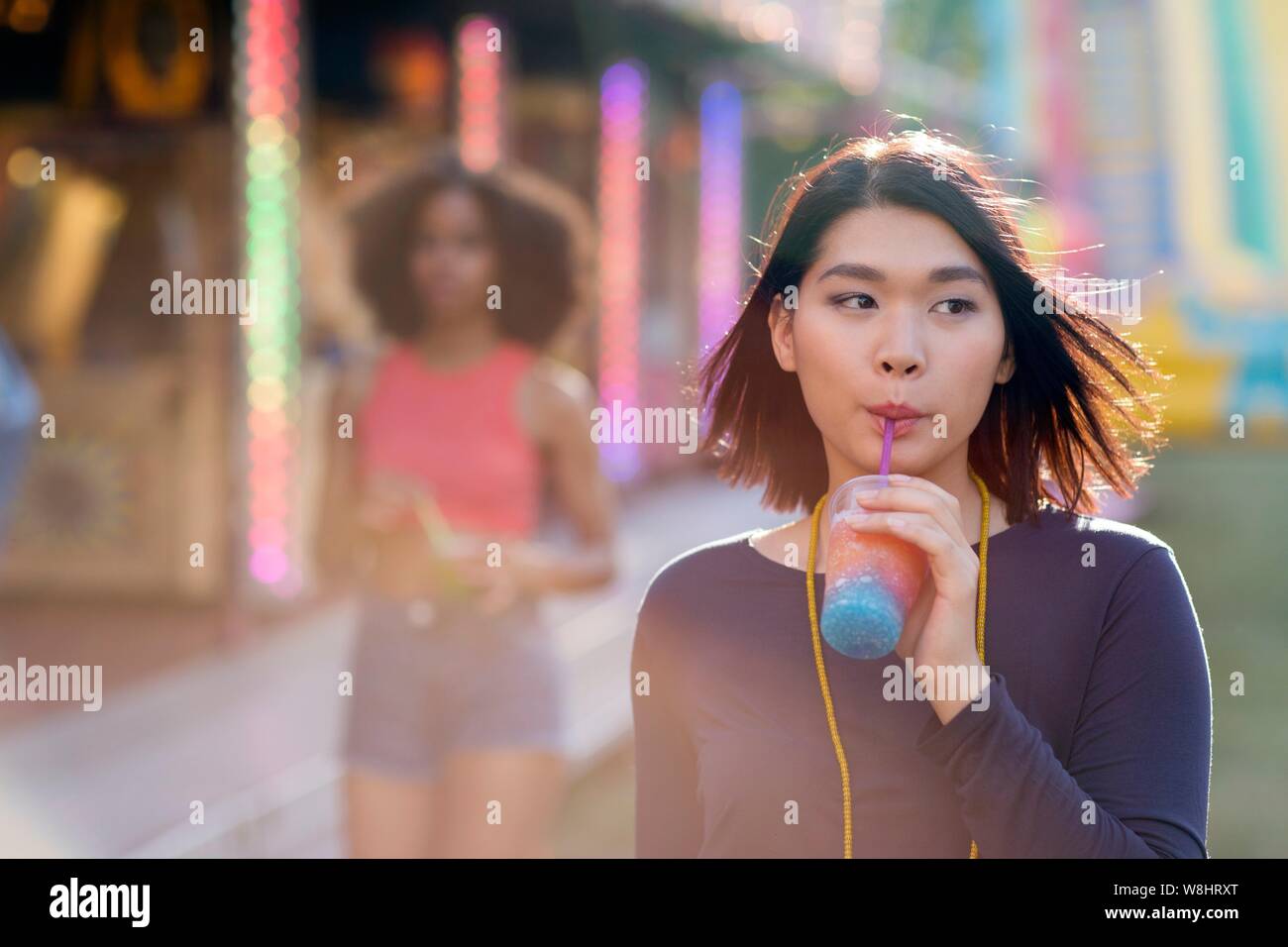 Junge Frau trinkt slushie an Kirmes. Stockfoto