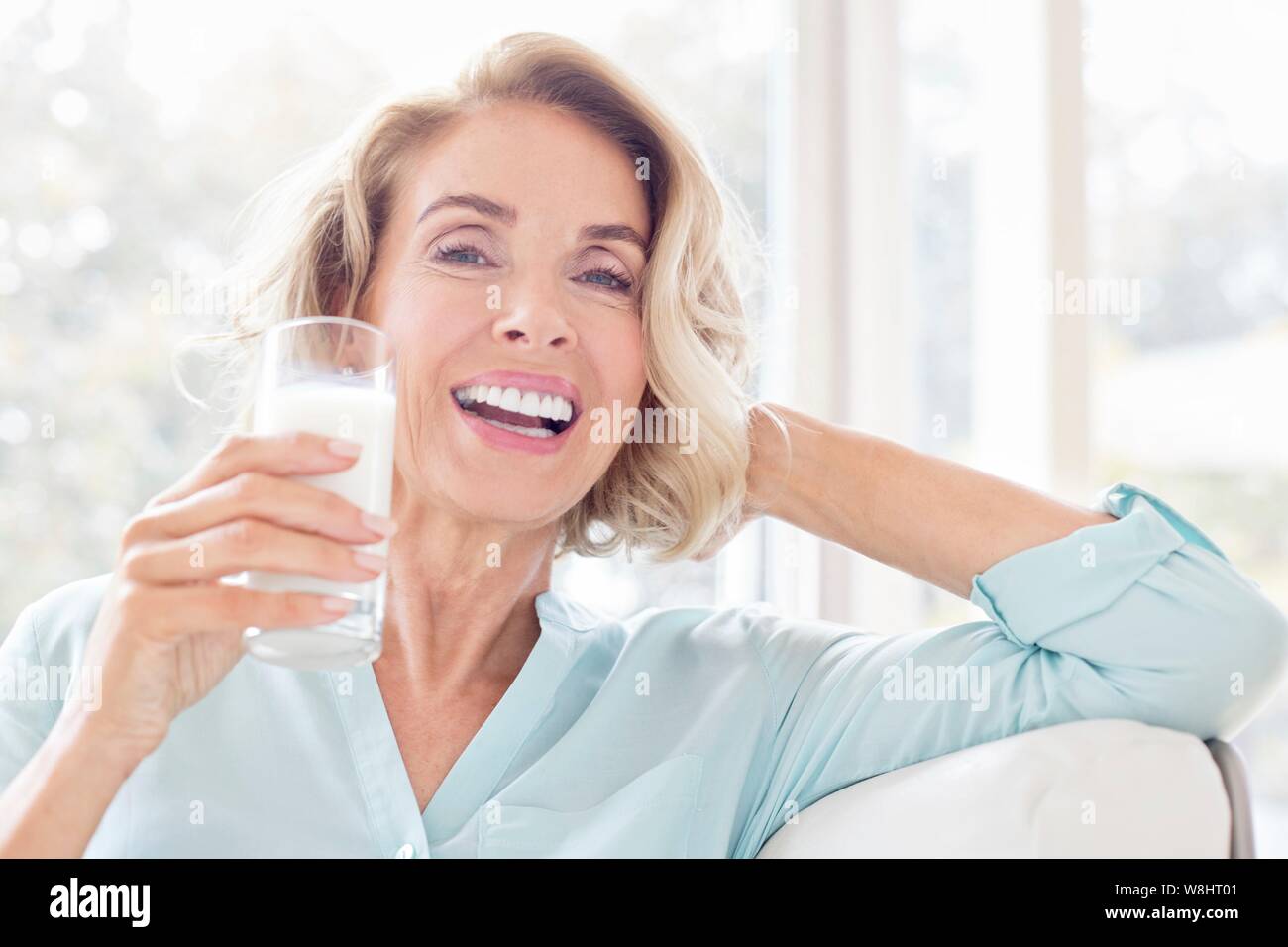 Reife Frau lächelnd mit Glas Milch. Stockfoto