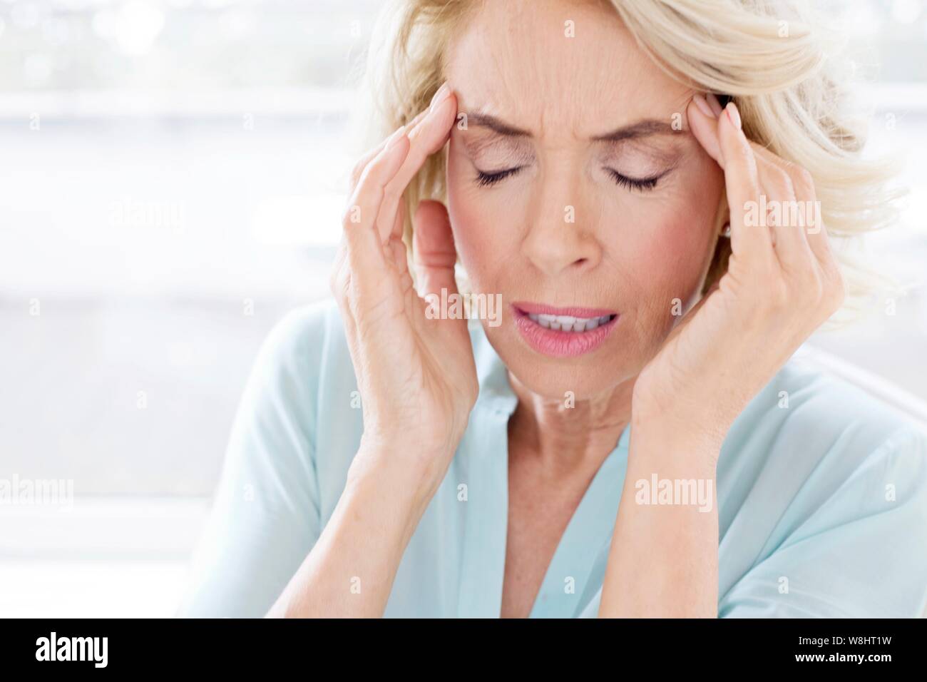 Reife Frau mit Kopfschmerzen. Stockfoto