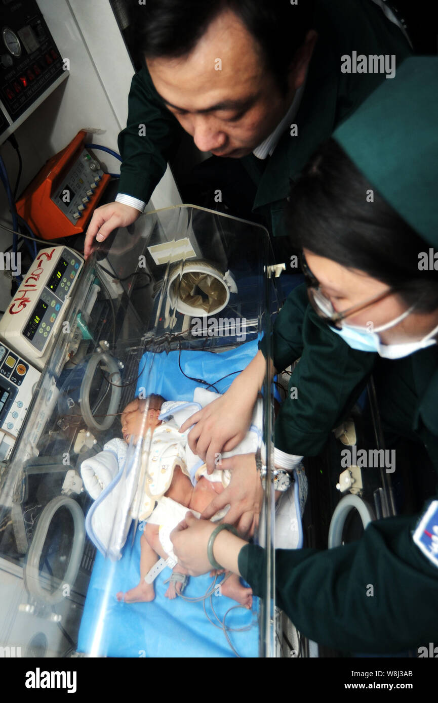 Chinesischen medizinischen Mitarbeiter kümmern sich um die siamesische Zwillinge in einem Inkubator in einem Krankenwagen, bevor sie an die Kinder Hospita übertragen wurden Stockfoto
