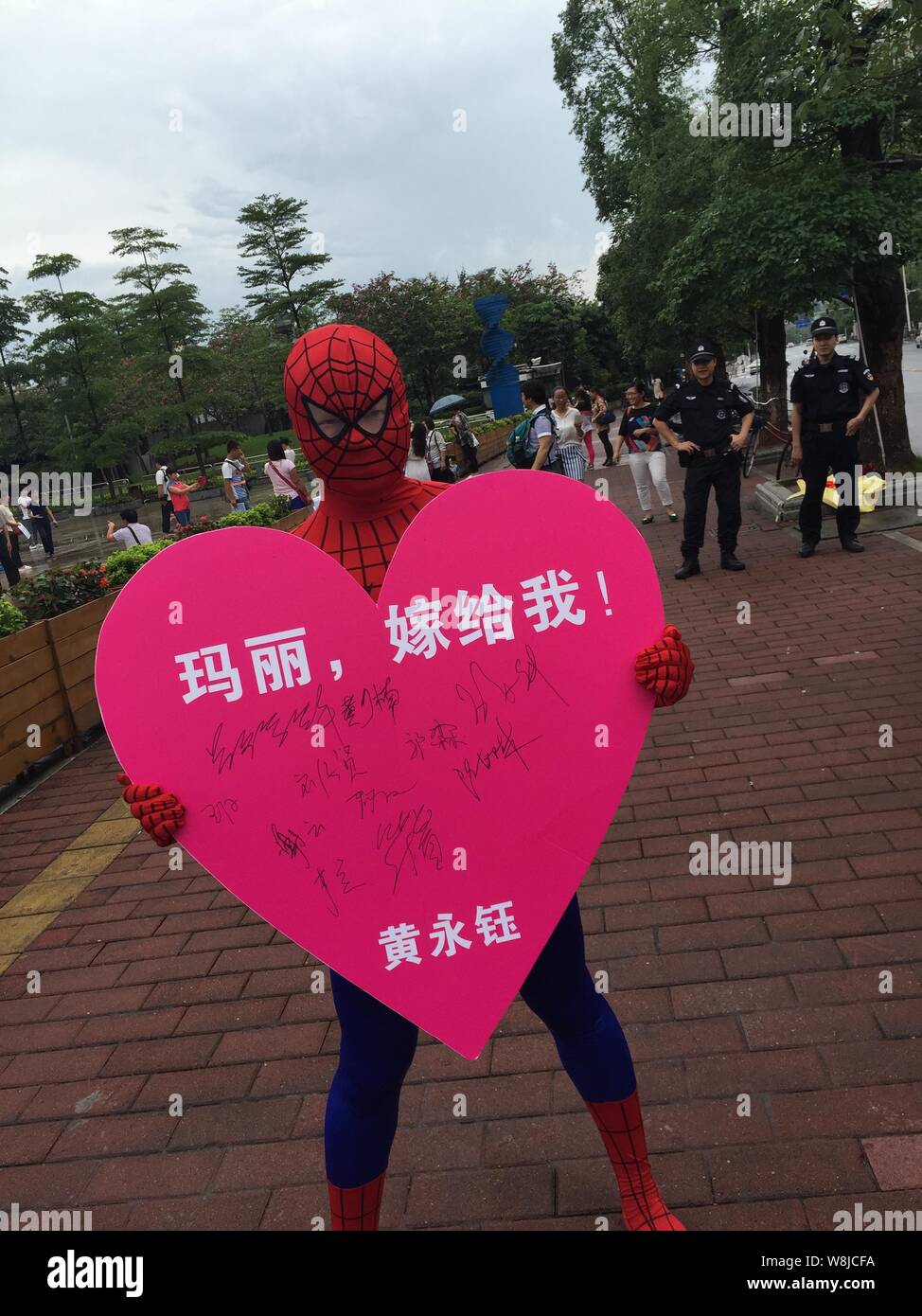 Ein Mann, gekleidet in der Spider-man Kostüm wirft mit einer herzförmigen Schild mit Unterschriften von 520 Fremden in Guangzhou City, South China Guangdong prov Stockfoto