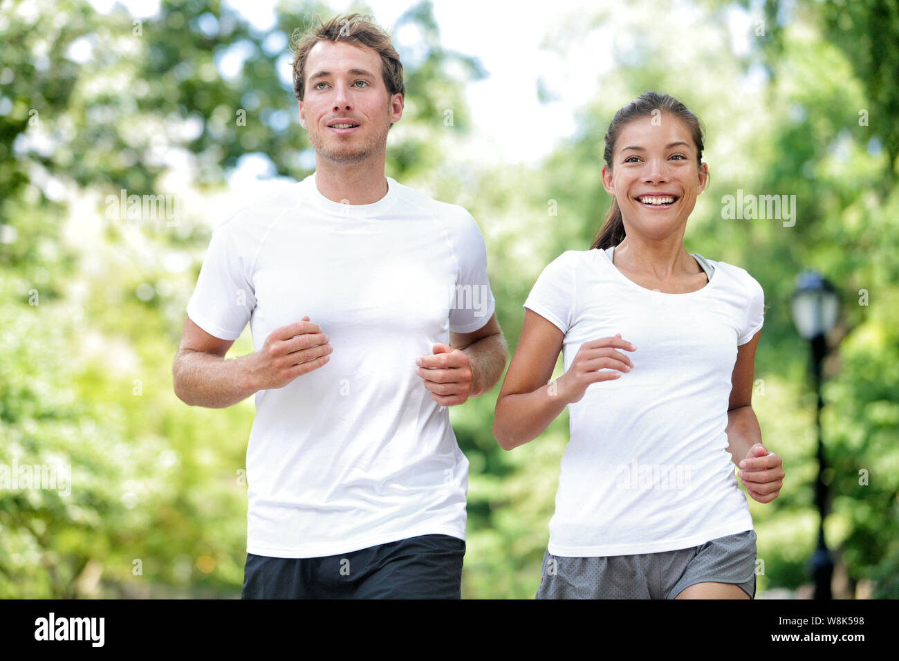 Fitness gesunde Lebensweise. Glückliches Paar, dass Sommer Training für Marathon im Central Park in Manhattan, New York. Asiatische weibliche model und kaukasische Sport Fitness männlichen Athleten joggen gemeinsam genießen. Stockfoto