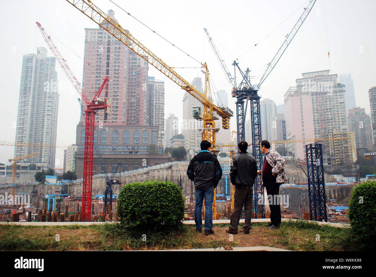 ------ Chinesische Männer an einem massiven Immobilien Baustelle in Chongqing, China, 26. November 2015. Der wirtschaftliche Erfolg der Metropolitan ein Stockfoto