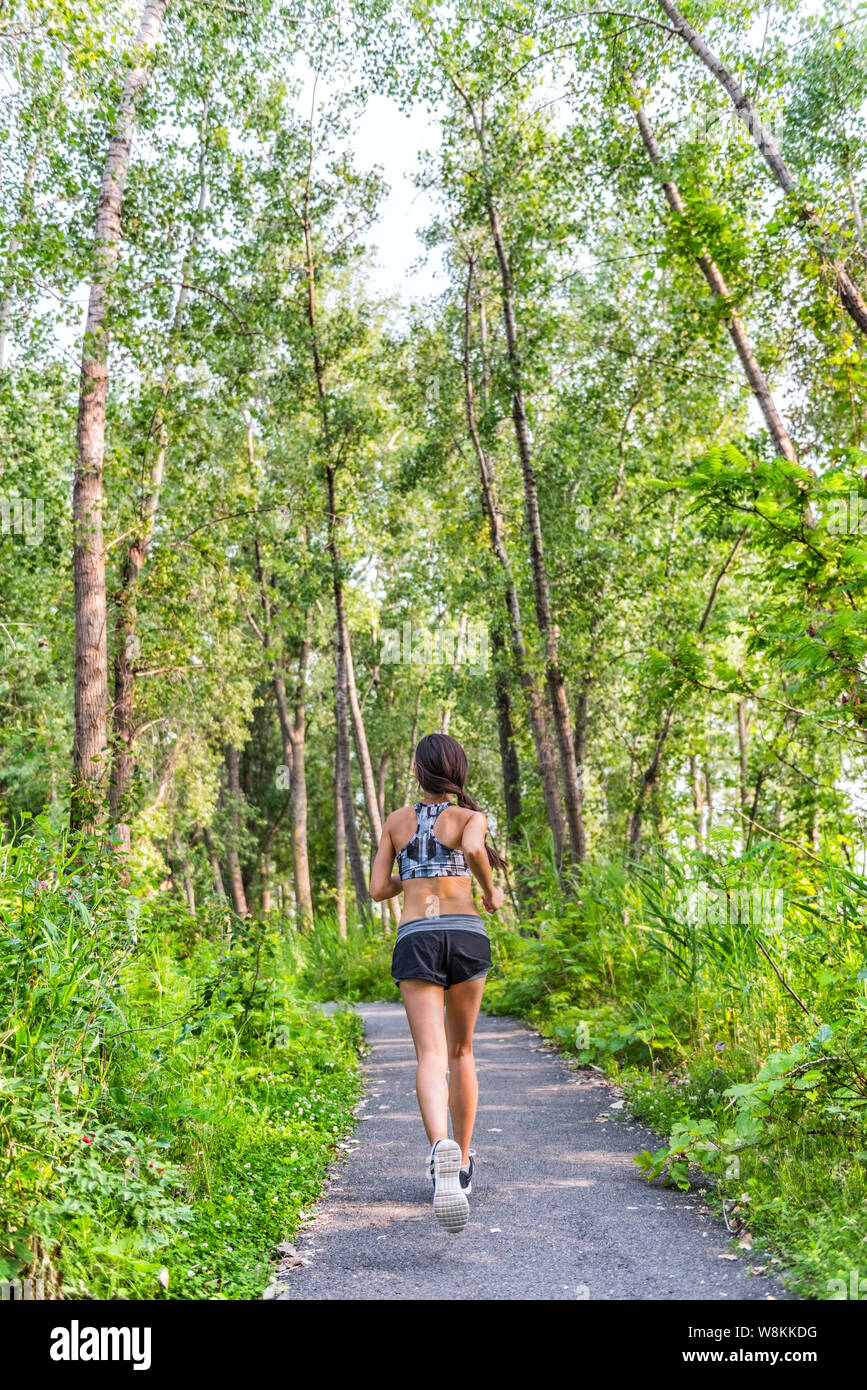 Runner Frau Training cardio auf Waldweg im Stadtpark im Sommer Natur. Zurück von Mädchen jogging leben ein gesunder aktiver Lebensstil Sport Sportbekleidung tragen Kleidung, die mit voller Länge. Stockfoto