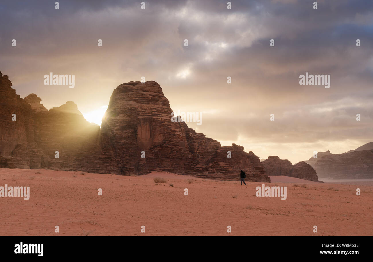 Wadi Rum wüste Landschaft im Sonnenaufgang. Ein Mann alleine im Wadi Rum Wüste in Jordanien, Naher und Mittlerer Osten Stockfoto