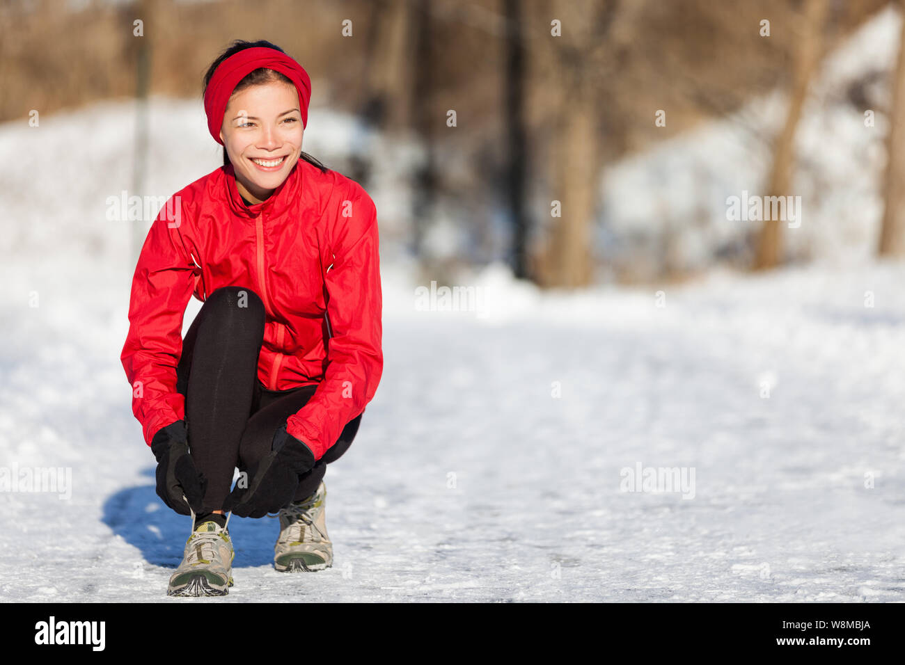 Ausführen von Athlet Frau Bereit für Outdoor laufen Laufschuhe schnüren Schnürsenkel während der Wintersaison. Außerhalb cardio Training in den kalten Schnee Wetter. Asiatische Mädchen mit Handschuhen, Stirnband und Jacke. Stockfoto