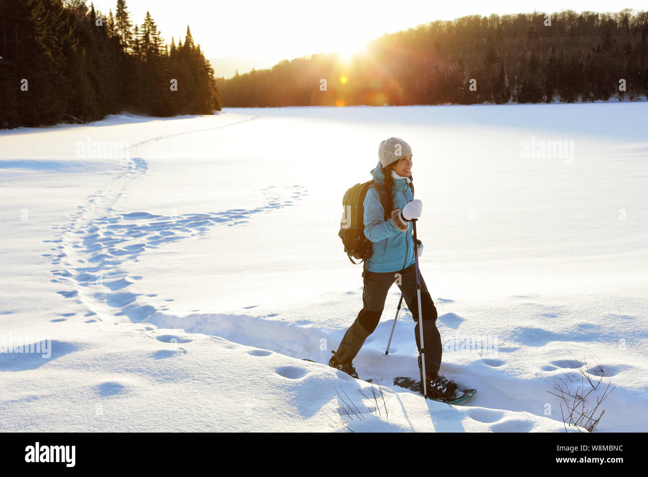 Winter Sport. Frau Wanderer wandern mit Rucksack und Schneeschuhen Schneeschuhwandern auf Snow Trail Wald in Québec, Kanada bei Sonnenuntergang. Schöne Landschaft mit Nadelbäumen und weißen Schnee. Stockfoto