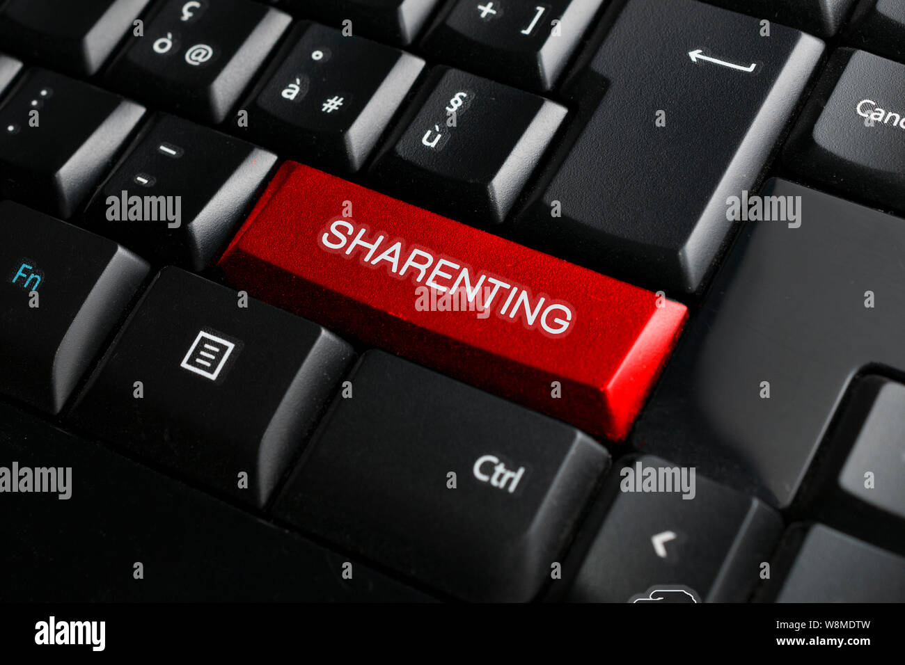 Sharenting (Übernutzung von Social Media durch die Eltern über ihre Kinder zu teilen) Konzept: Tastatur in Schwarz mit einem roten Schlüssel und der sharenting Wort Stockfoto