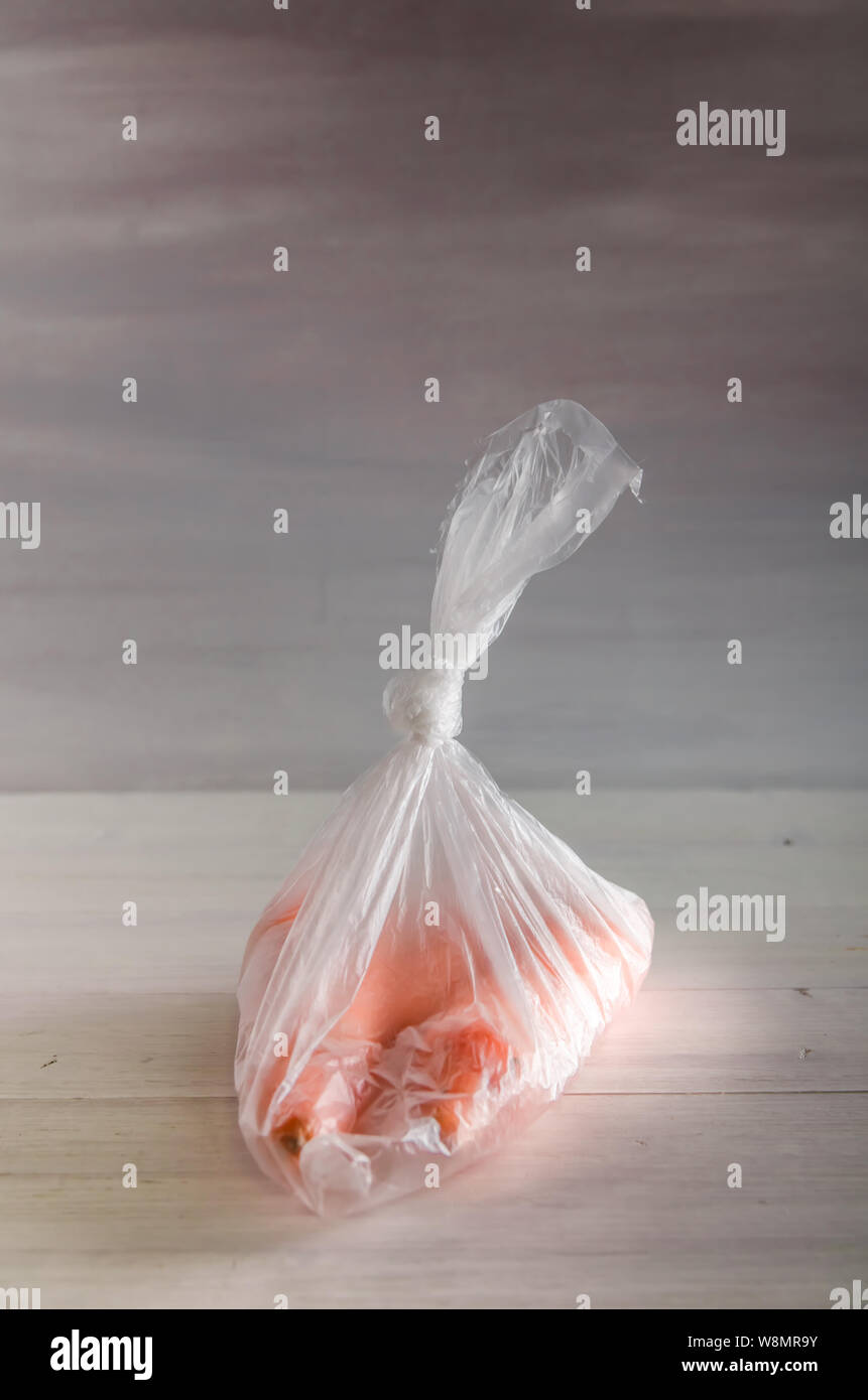 Konzept Kunststoff sich Karotten in einer Plastiktüte auf weißem Hintergrund mit Kopie Raum Stockfoto