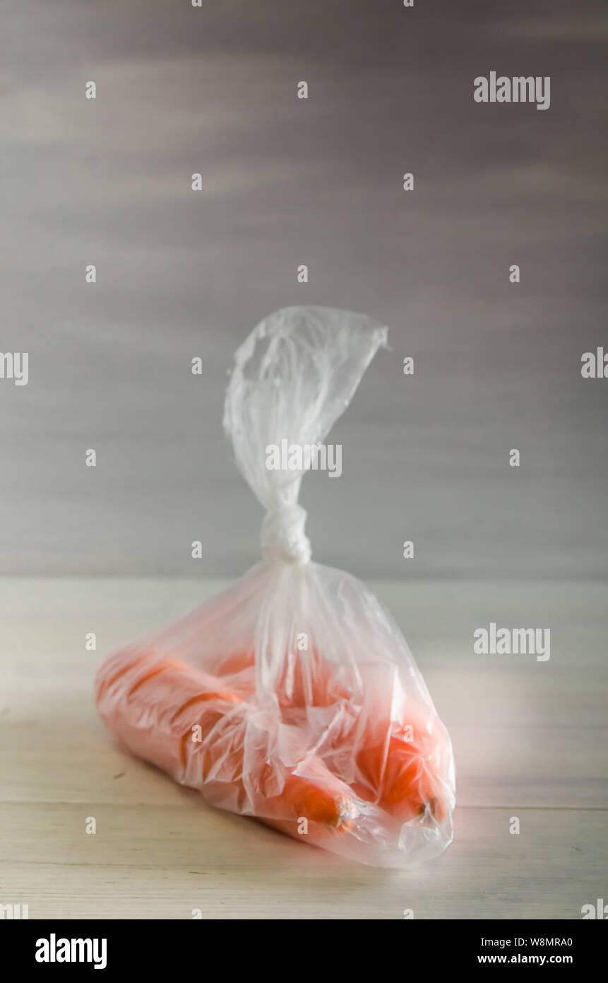 Konzept Kunststoff sich Karotten in einer Plastiktüte auf weißem Hintergrund mit Kopie Raum Stockfoto