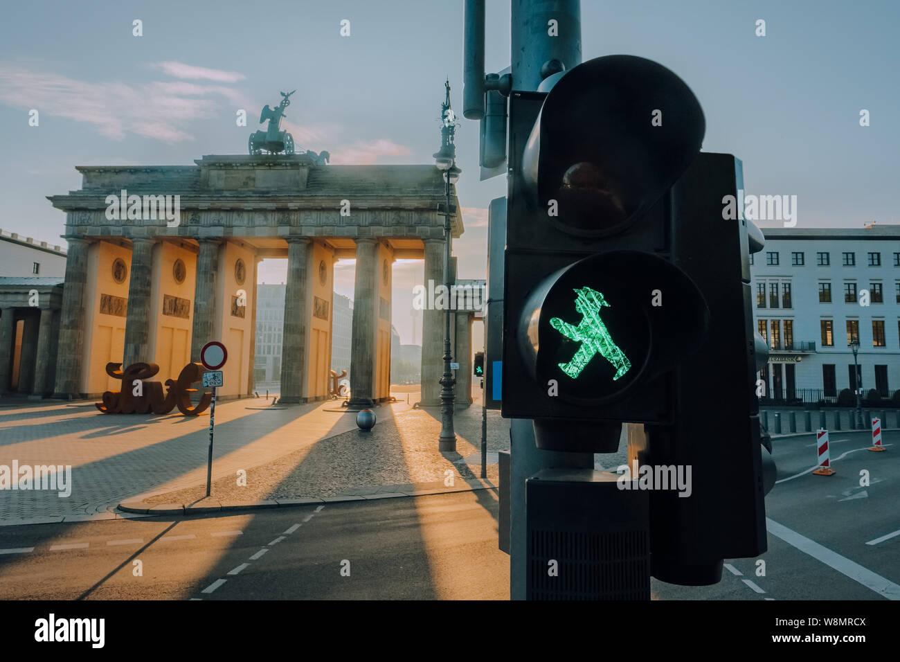 Ampelmann Berlin grüne Ampel close-up mit Brandenburger Tor im Hintergrund bei Sonnenaufgang Stockfoto