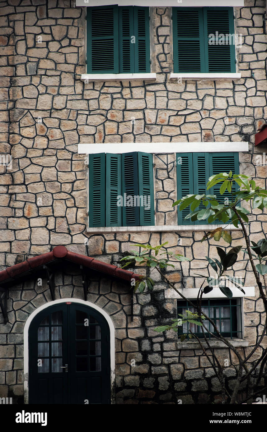 Erstaunlich französischer Architektur des alten Steinhaus mit grünem Holz- Fenster und Türen, Stoßfänger Steinmauer von Villa in die Geschichte, Da Lat, Vietnam Stockfoto