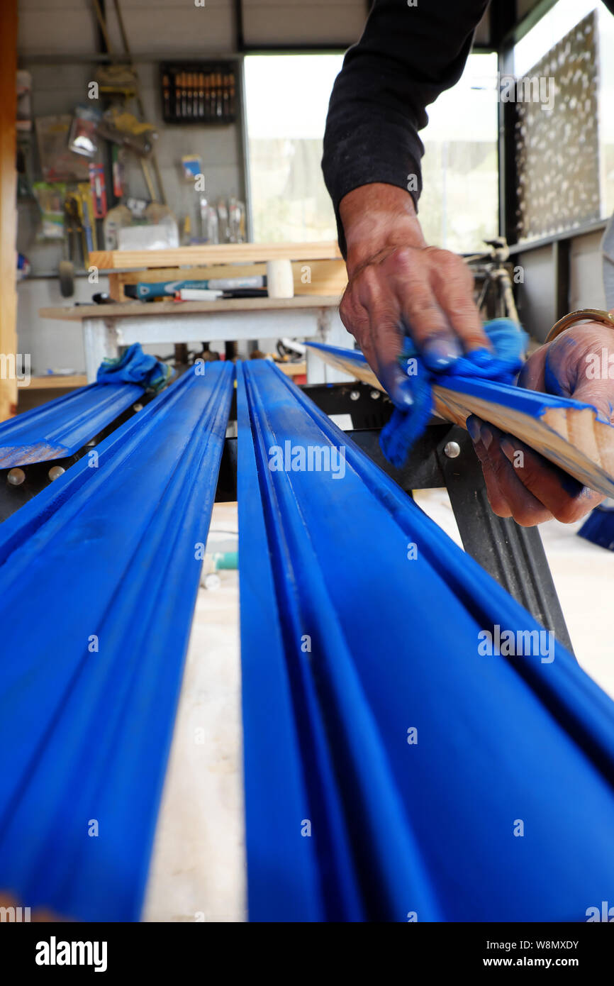 Vietnamesische Mann bei der Arbeit in der Werkstatt, männliche Hände malen auf Bar aus Holz mit blauer Lackierung, Menschen tun es sich Möbel für zuhause Da Lat Stockfoto