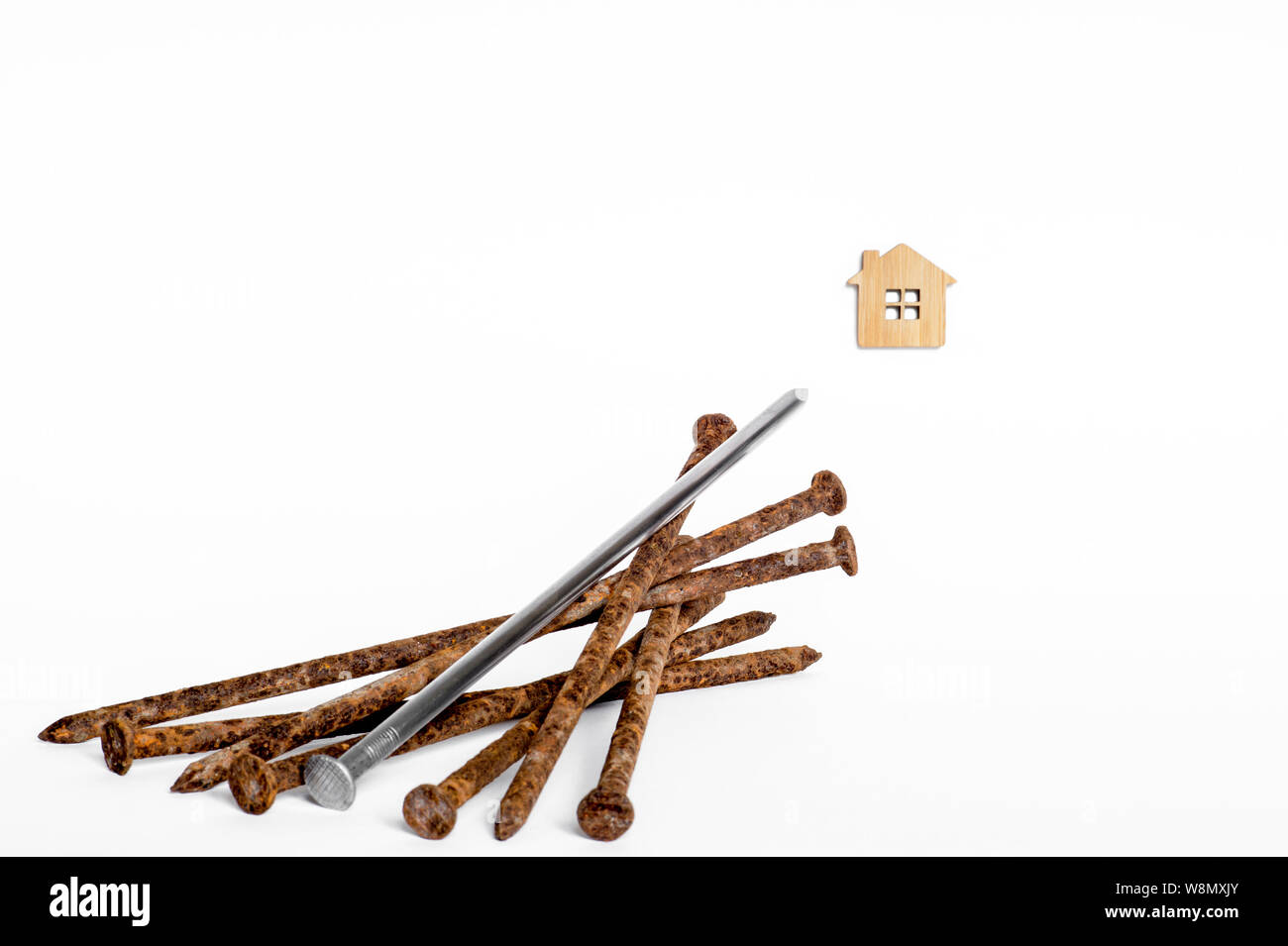 Ein glänzendes Metall Nagel liegt auf einem Stapel von alten rostigen Nägeln und ist im Haus Symbol auf weißem Hintergrund. Stockfoto