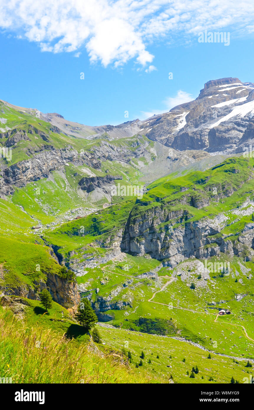 Vertikale Bild der alpinen Landschaft fotografiert an einem sonnigen Tag. Wanderwege durch Felsen, Berge und grüne Wiesen. Schweizer Landschaft. Swit Stockfoto