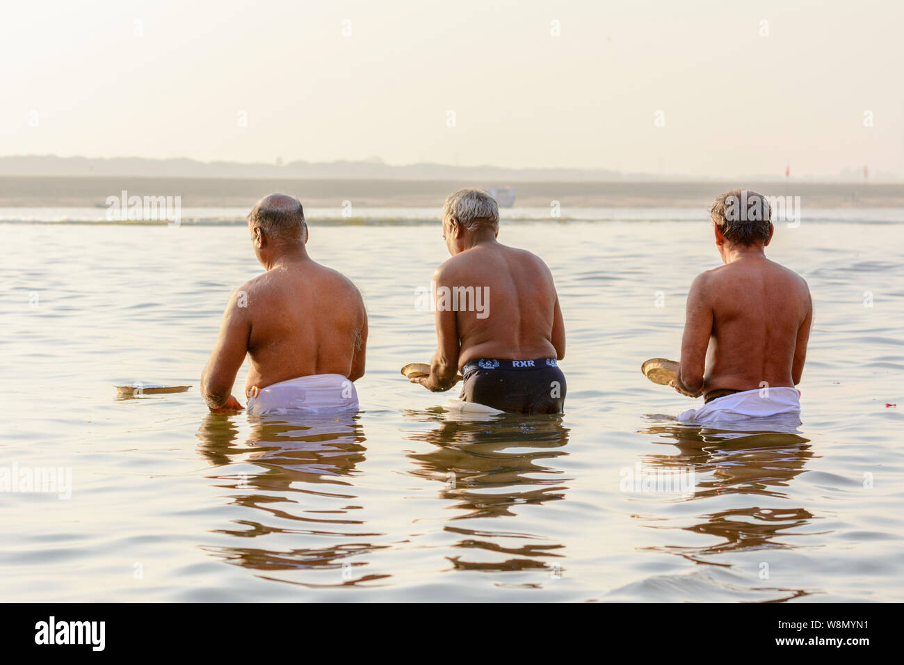 Drei indische Männer (Pilger) Gaben an die Götter (Hebe) im Fluss Ganges in Varanasi, Uttar Pradesh, Indien, Südasien. Stockfoto