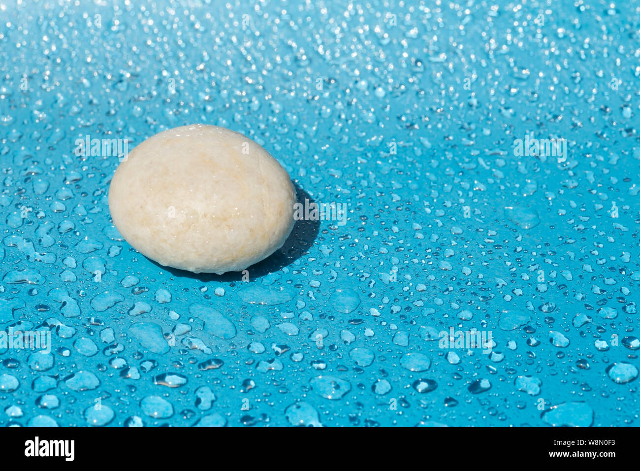 Einzigen Stein Weiß auf Blau Wassertropfen Hintergrund Stockfoto