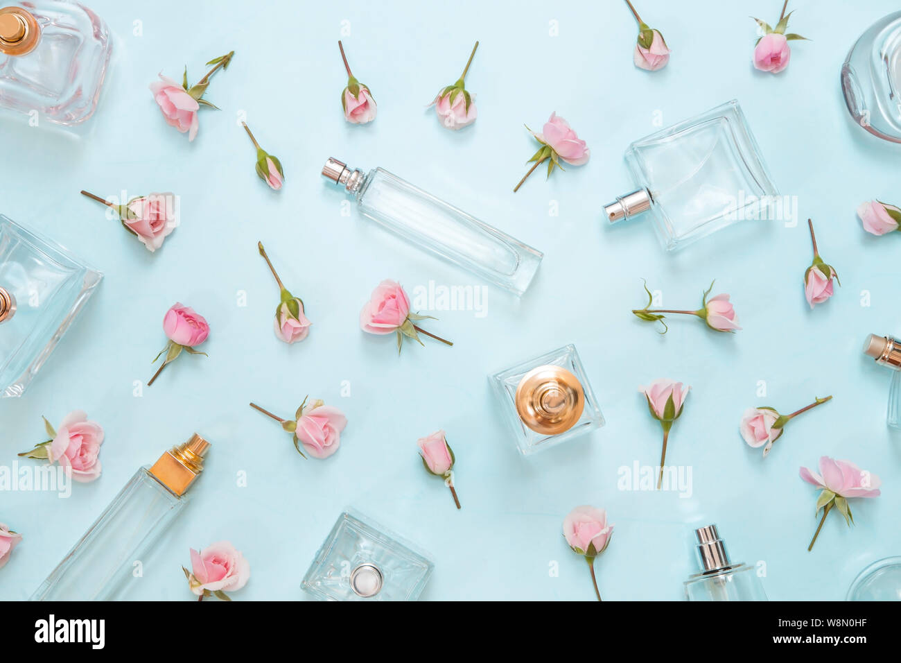 Parfümflakons und Rosen auf blauem Hintergrund - Ansicht von oben Stockfoto