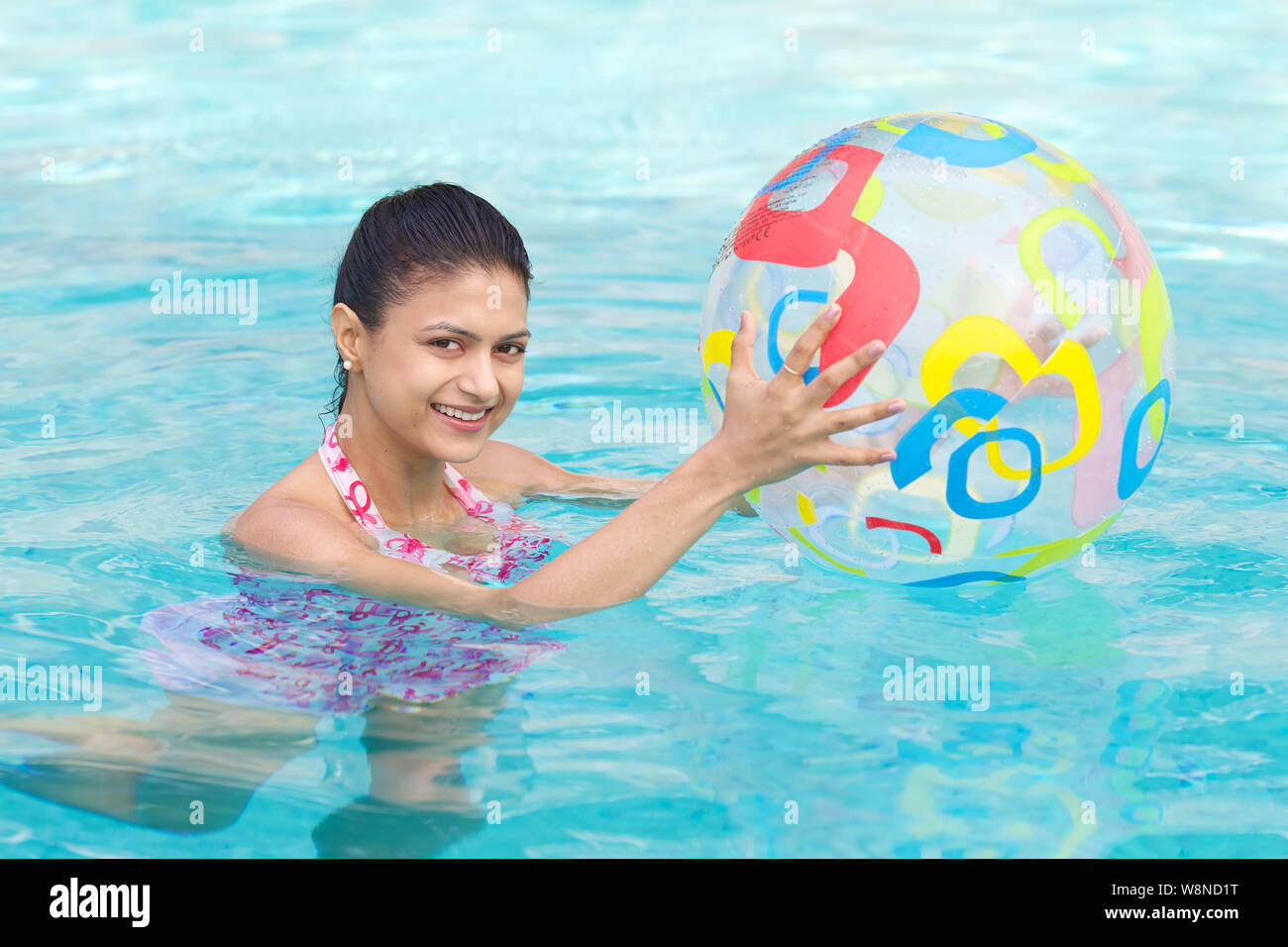 Junge Frau spielt mit einer Kugel in einem Pool Stockfoto