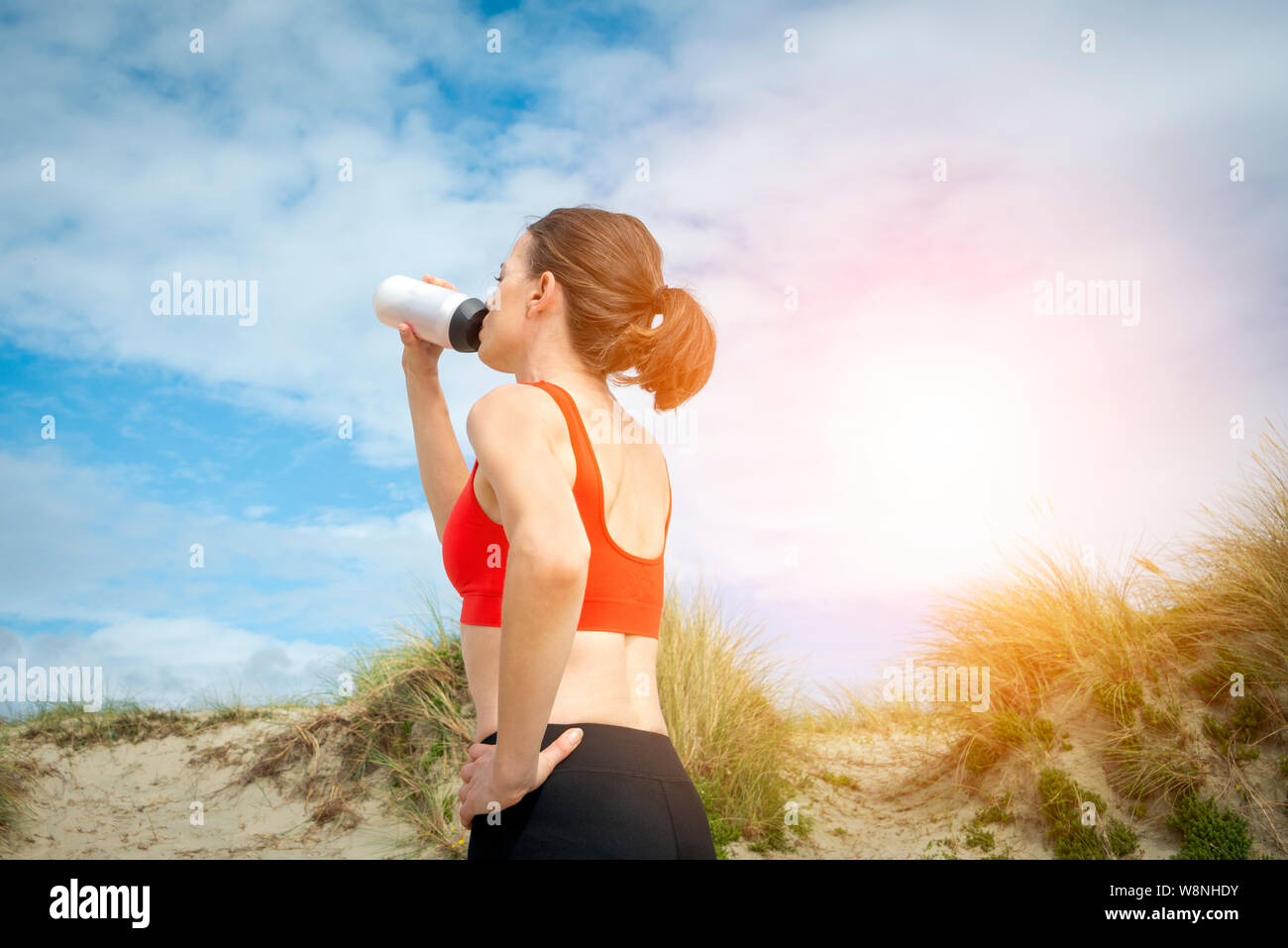 Frau trinkt aus einem Kunststoff Trinkflasche nach dem Training in der Sonne Stockfoto