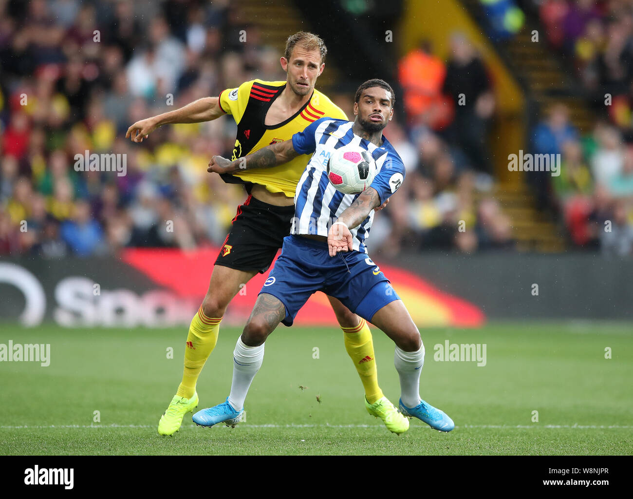 Die watford Craig Dawson (links) und Brighton und Hove Albion Jurgen Locadia Kampf um den Ball während der Premier League Match an der Vicarage Road, Watford. Stockfoto