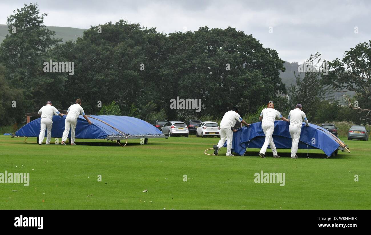 Spieler bewegen Sie die Abdeckungen auf der wicket als Regen das Match zwischen Charlesworth und Chisworth CC und Mottram 2 Team Interrupts Stockfoto