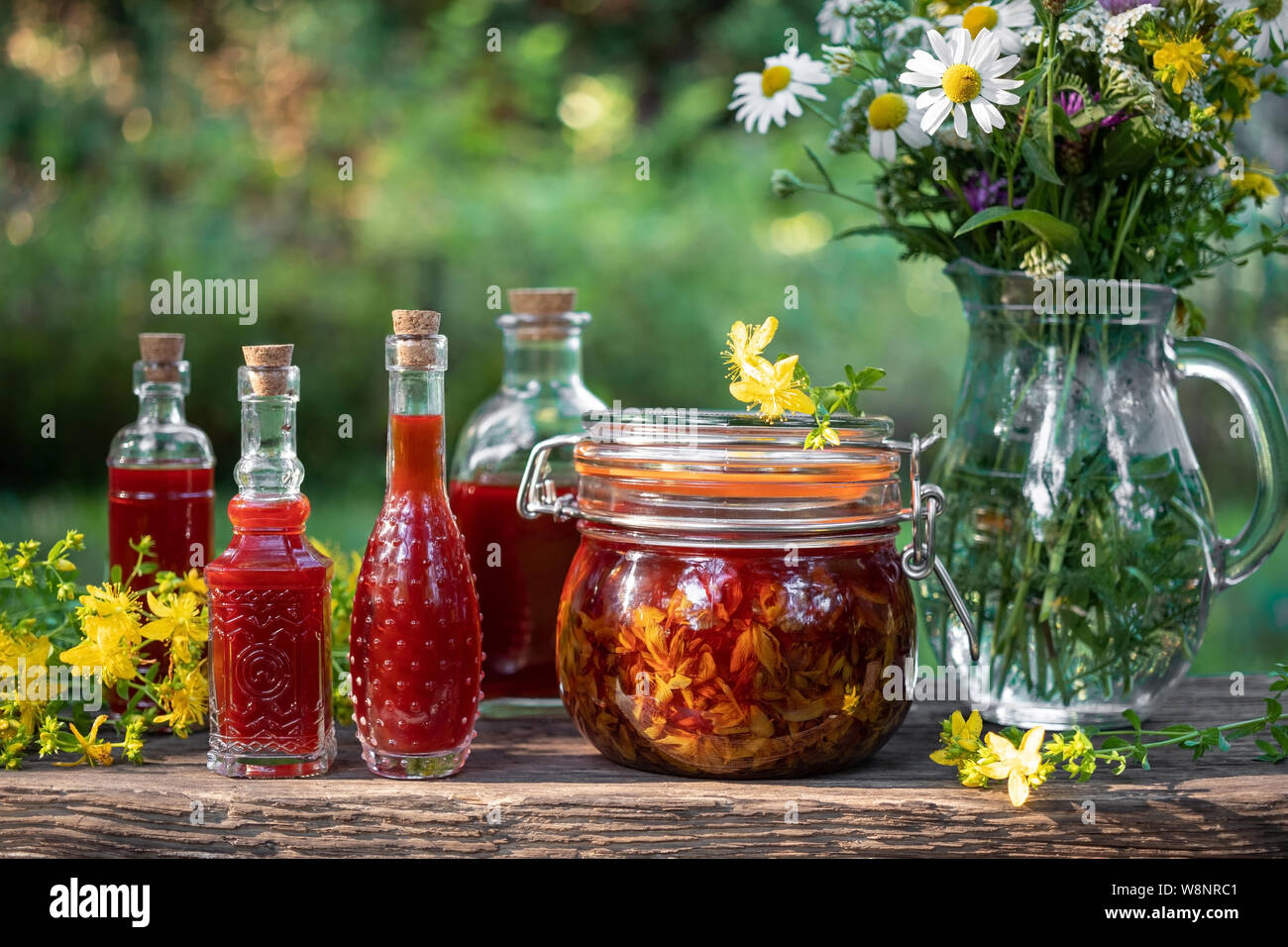 Flaschen mit roter Öl aus Johanniskraut Blüten, in einem Garten fotografiert gemacht Stockfoto