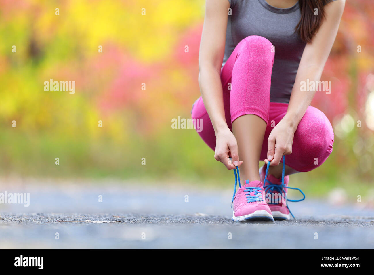 Laufschuhe - Frau Schnürsenkel binden. Nahaufnahme der weiblichen Sport Fitness runner Fertig zum Joggen im Freien auf Waldweg im Spätsommer oder Herbst. Stockfoto