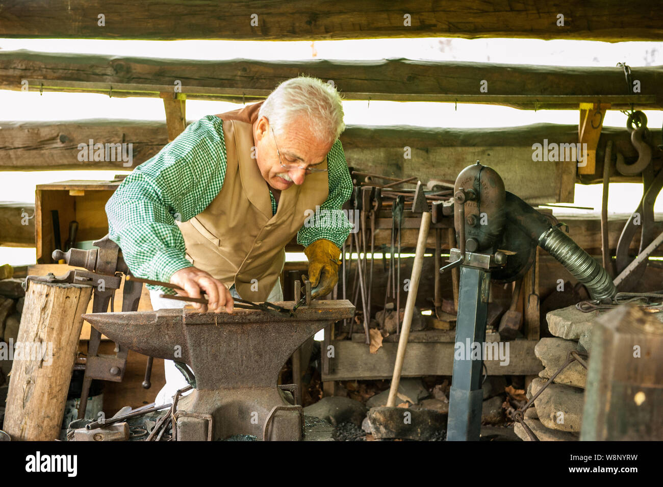 Townsend, TN/April 15, 2012: Ältere Mann arbeitet auf den Amboss in einer alten Schmiede für Touristen der Great Smoky Mountain National Park. Stockfoto