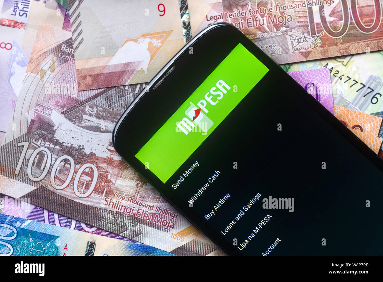 Safaricom M-Pesa fintech Mikrofinanz geld Transaction Service am Telefon mit neuen kenianischen Schilling Banknoten Hintergrund Stockfoto