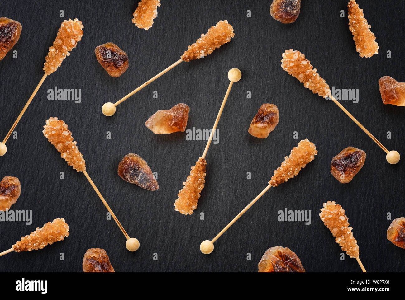 Flach brauner Zucker auf einem Stick als Muster auf schwarzem Schiefer Hintergrund. Ansicht von oben Stockfoto