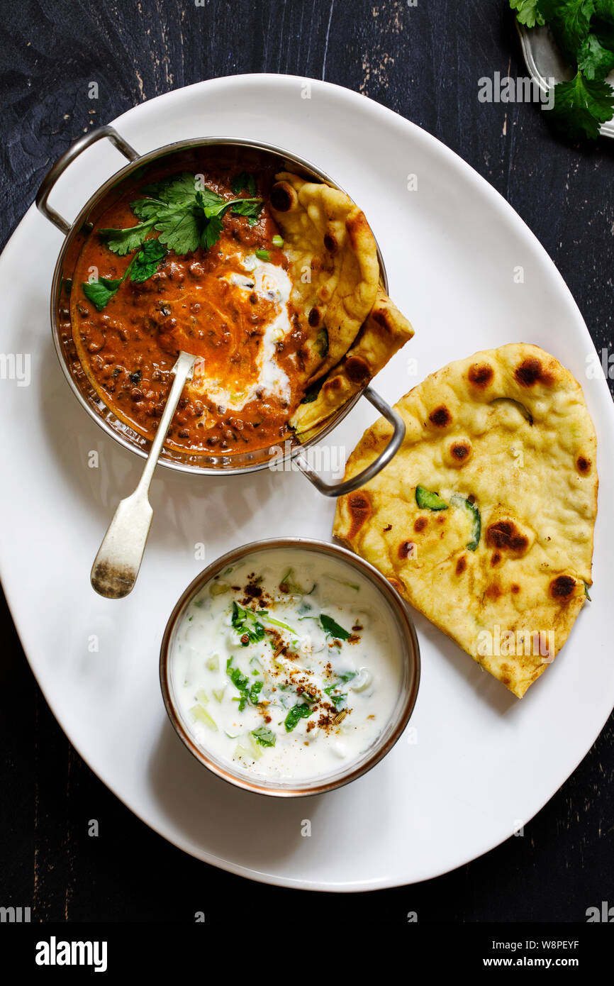 Indisches essen Curry mit schwarzen Linsen dal, Naan Brot und raita Stockfoto