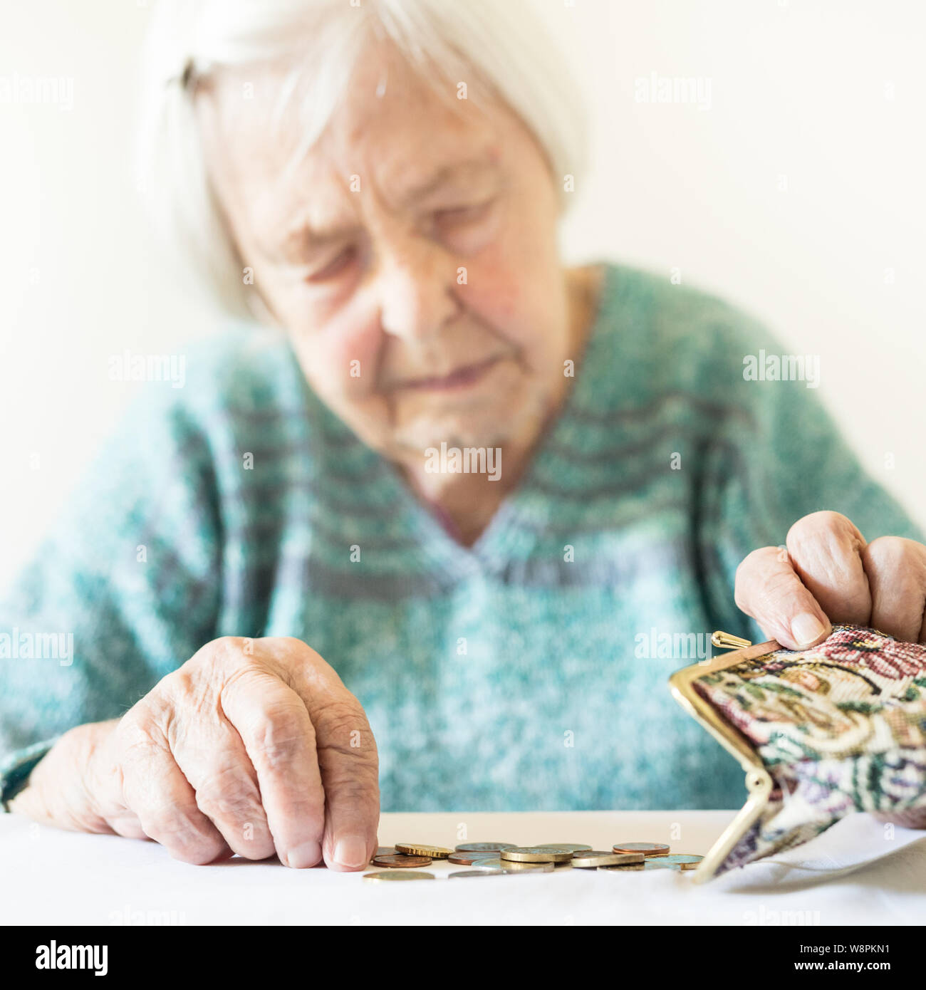 Betroffene ältere Frau am Tisch sitzen zählen Geld in Ihrem Portemonnaie. Stockfoto