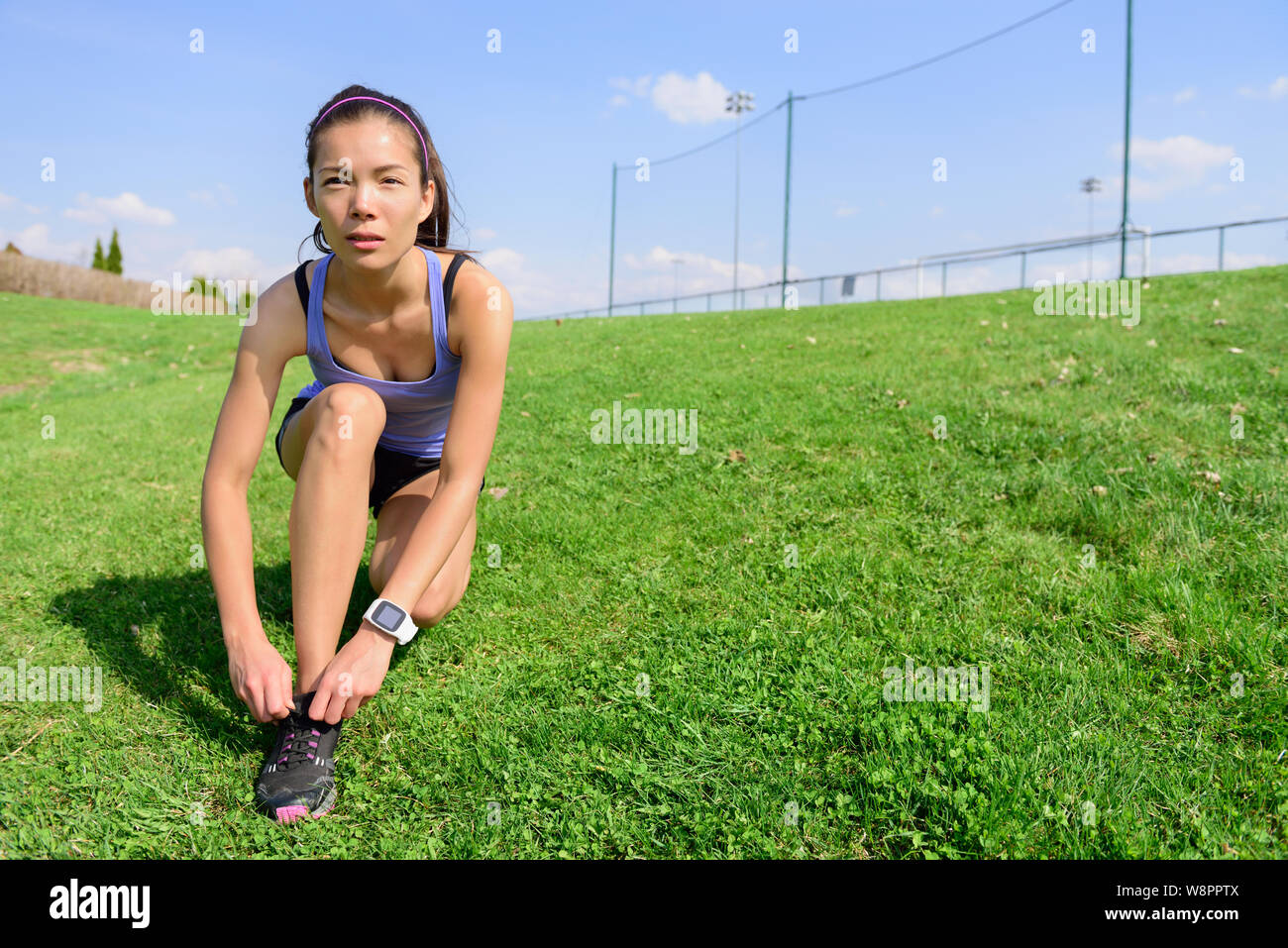 Sportliche Frau runner Vorbereitung für den Betrieb binden Schnürsenkel in Morgen auf der Rasenfläche. Wellness und gesunden Lebensstil Konzept mit gemischten Rennen asiatischen Kaukasischen weibliche Modell gehen. Stockfoto