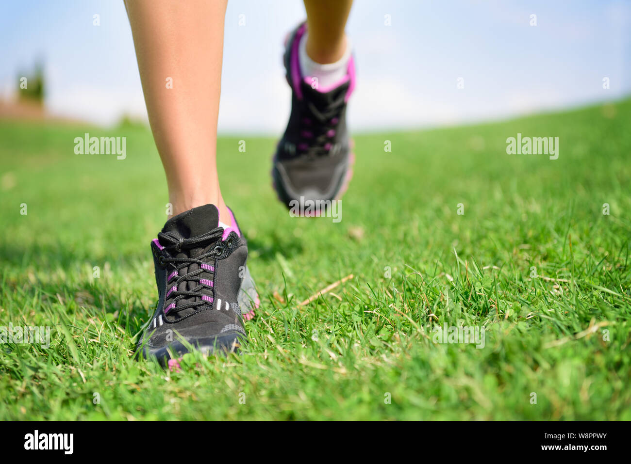 Runner Athlet Füße laufen auf Gras. Fitness Frau jog Workout und Wellness Konzept. In der Nähe der weiblichen Laufschuhe und Beinen. Stockfoto