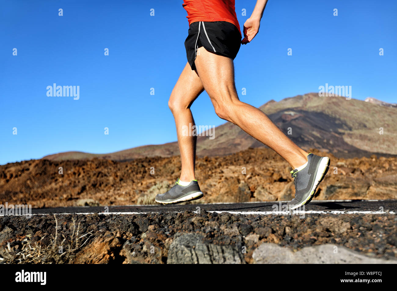 Ausführen von Athlet mann Läufer joggen auf Natur Straße in Wald Berg. Die untere Hälfte des Körpers Laufschuhe und Beine der männlichen Erwachsenen auf dem Joggen im Sommer. Stockfoto