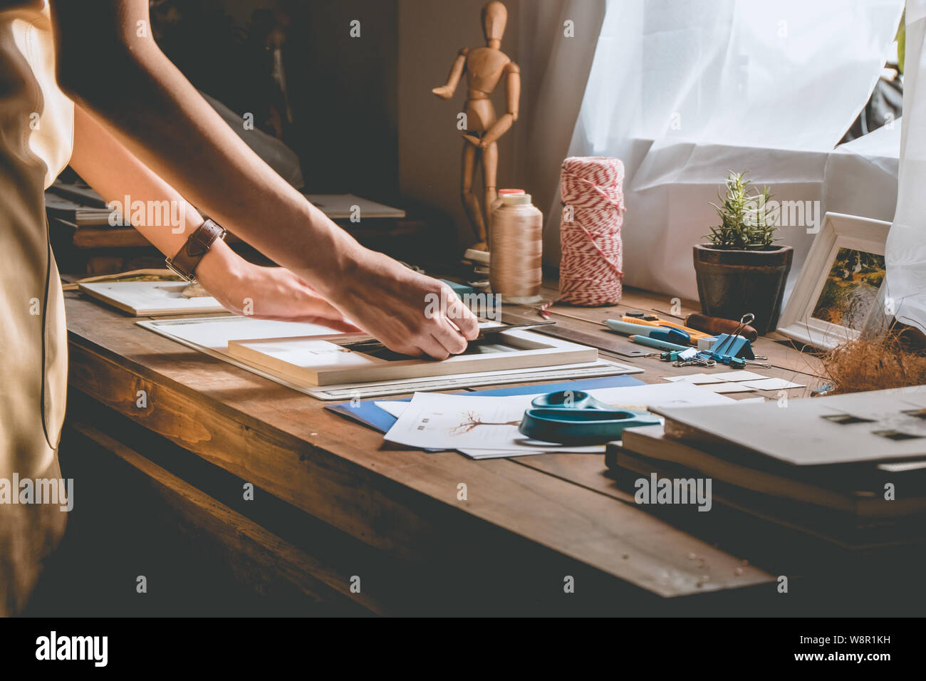 Schöne Frau hand Buch Crafting an der Tischplatte mit Schreibwaren. Stilvolle Handwerkerin mit Vorlage der Arbeit an seinem hipster Workstation. Stockfoto