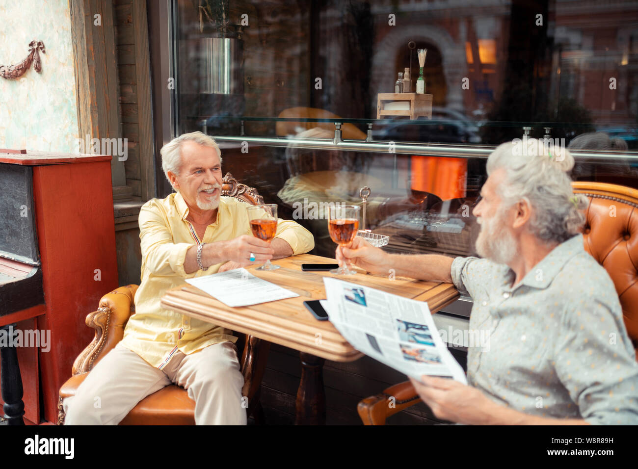 Pensionierte Männer klirrendes Glas, während das Trinken von Alkohol Stockfoto