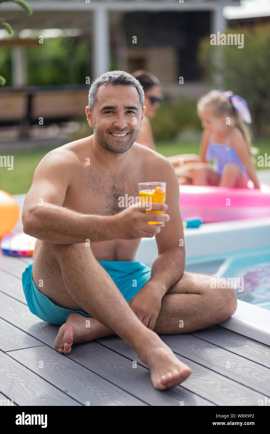 Bärtige Vater sitzt in der Nähe der Pool mit seiner Frau und seiner Tochter Stockfoto
