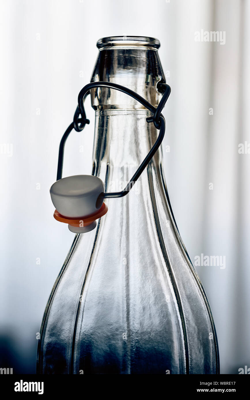 Detail einer Glas Flasche mit einem Drahtbügel Verschluss keramischen Stopfen vor dem Fenster mit weißen Vorhang Stockfoto