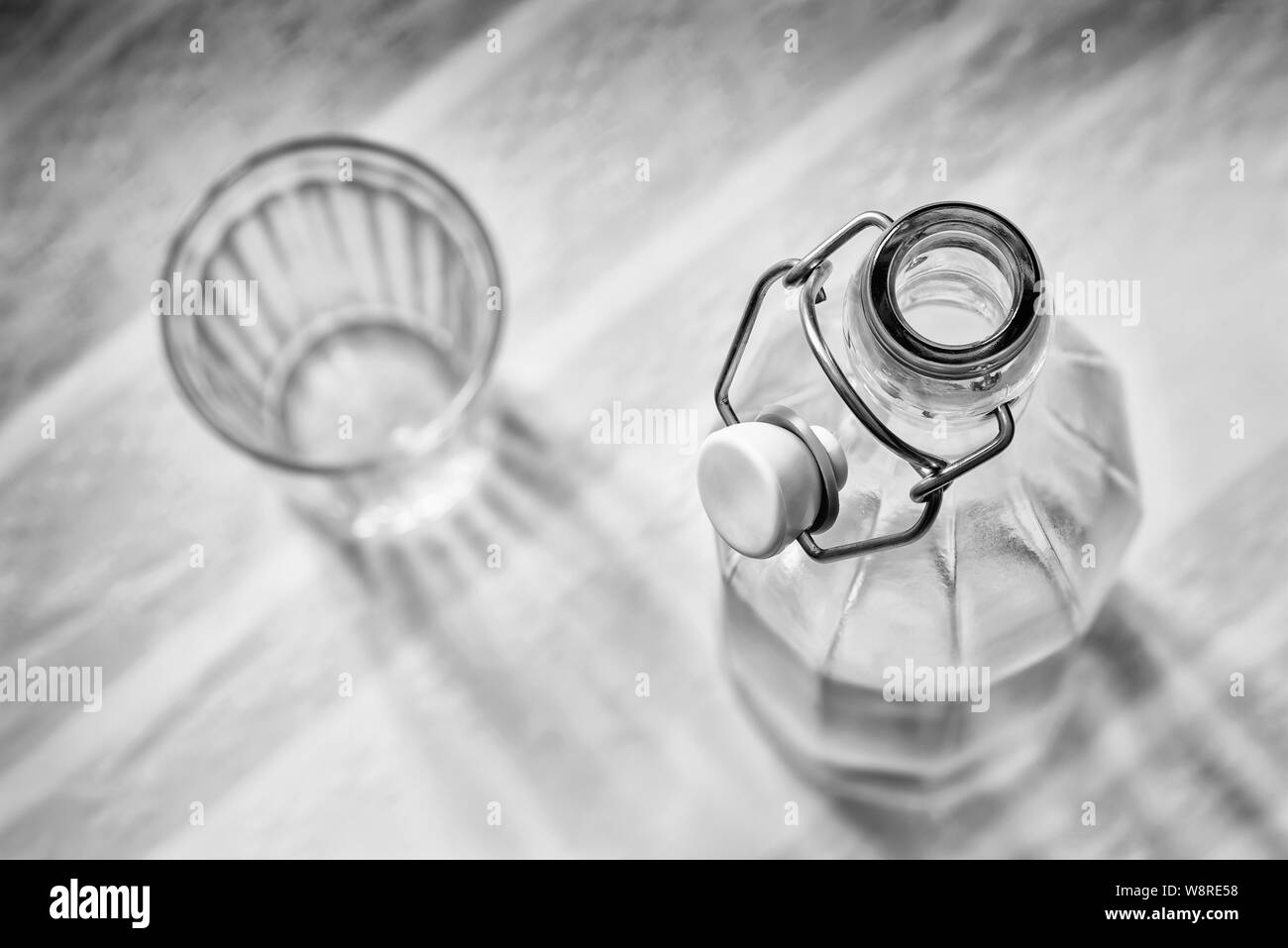 Ansicht von oben in eine Glasflasche mit einem Drahtbügel Verschluss keramischen Stopfen, und ein Getränk Glas, blau, pink und orange abgestreift Tischdecke Stockfoto