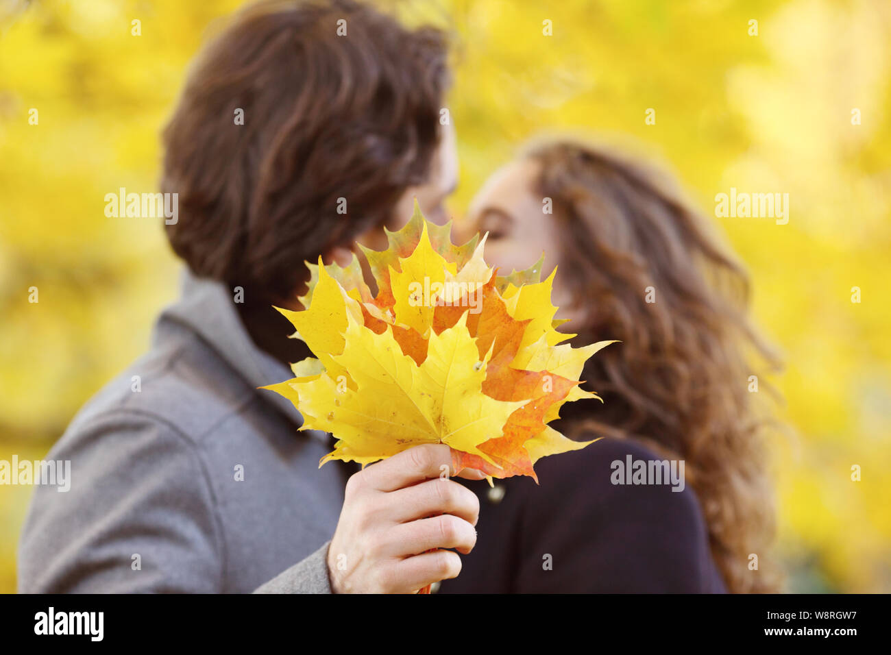 Liebe, Beziehung, Familie und Personen Konzept - Paar mit Ahorn Blätter im Herbst Park küssen Stockfoto