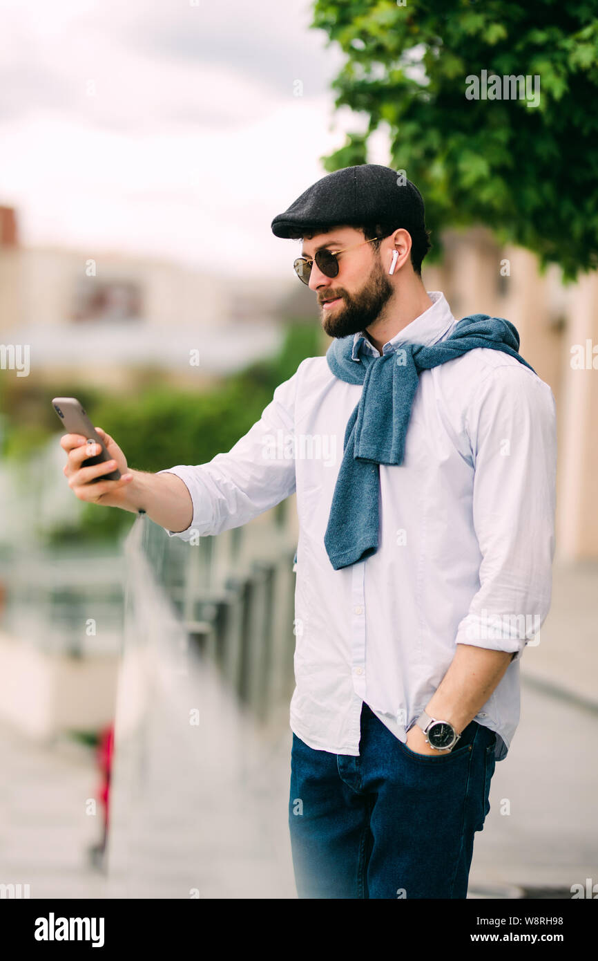 Junge, urbane, Geschäftsmann auf dem Smartphone zu Fuß auf der Straße mit "App sms sms-Nachricht auf dem Telefon Stockfoto