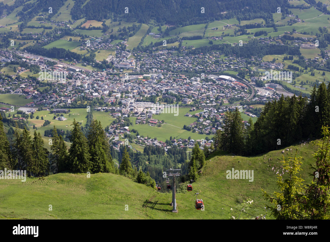 Blick im Sommer über das Dorf Kitzbühel, Österreich von den Pisten der Hahnenkamm-Abfahrt mit der Seilbahn im Vordergrund. Stockfoto