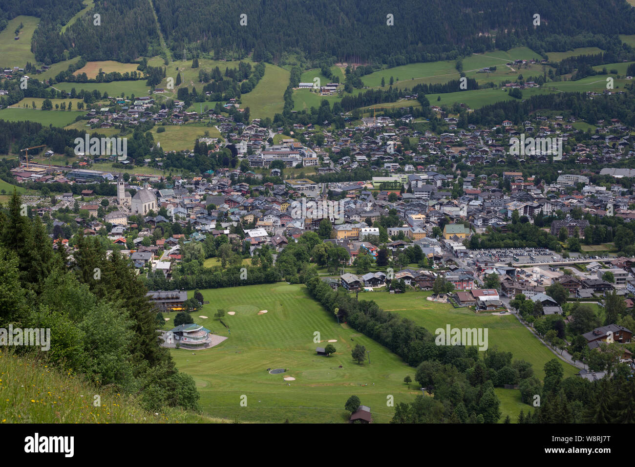 Blick im Sommer über das Dorf Kitzbühel, Österreich von den Pisten der Hahnenkamm-Abfahrt mit dem Golfplatz im Vordergrund. Stockfoto