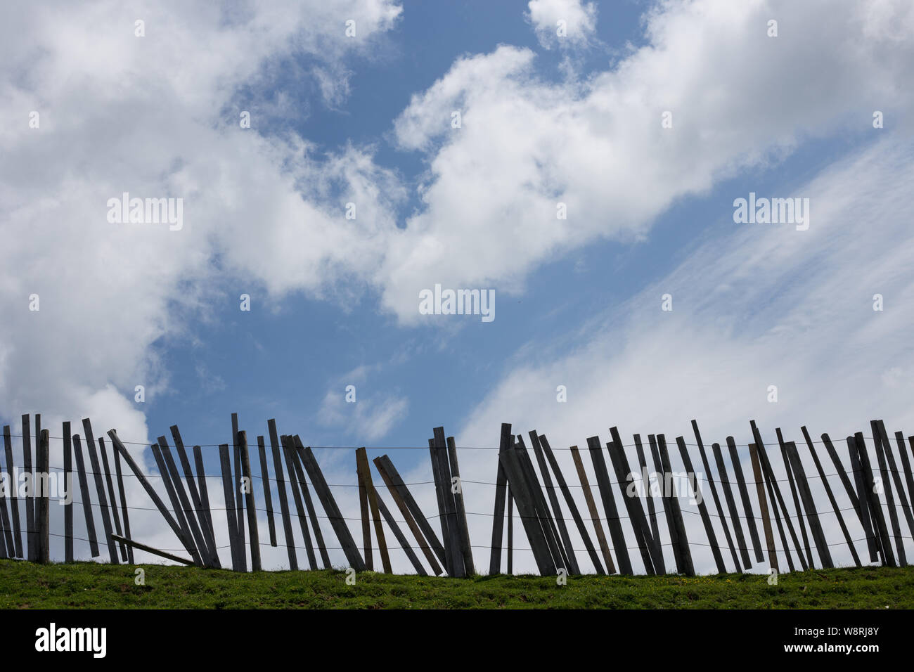 Eine hölzerne Pfosten und Zaun gegen den blauen Himmel und Wolken Silhouette Stockfoto