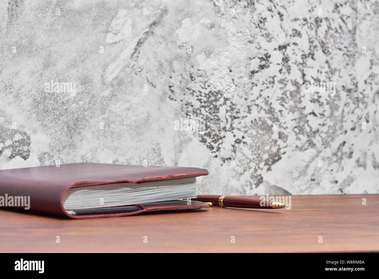 Organizer mit Stift auf dem Holz Tisch vor der Betonwand. Grau Loft style Wand benutzen für den Hintergrund. Stockfoto