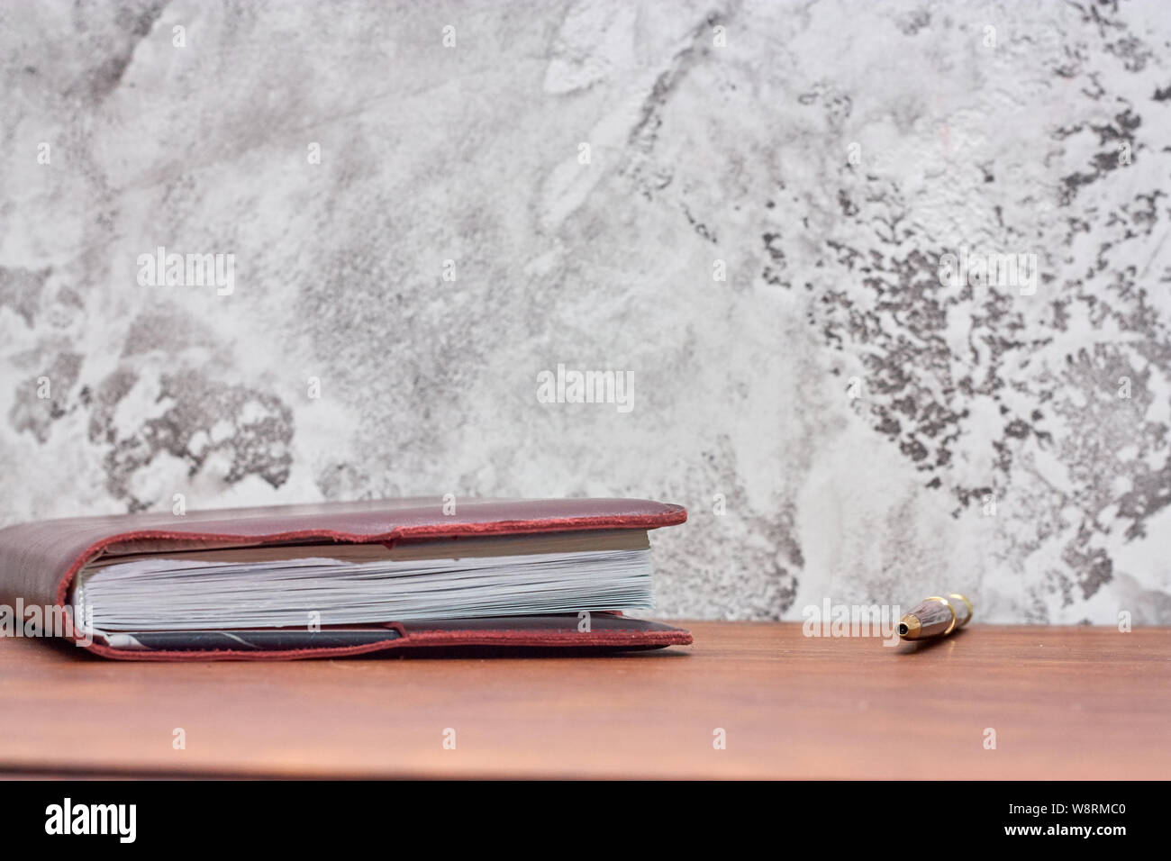 Organizer mit Stift auf dem Holz Tisch vor der Betonwand. Grau Loft style Wand benutzen für den Hintergrund. Stockfoto