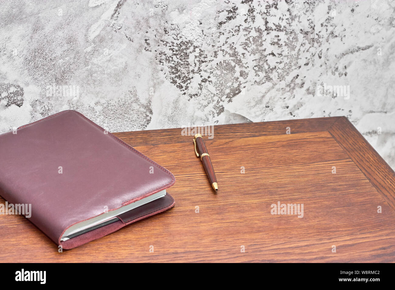 Organizer mit Stift auf dem Holz Tisch vor der Betonwand. Grau Loft style Wand benutzen für den Hintergrund. Stockfoto