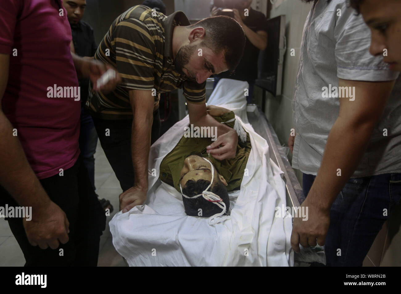 Gaza, den Palästinensischen Gebieten. 11 Aug, 2019. Verwandte von Marwan Nasser, der schießen tot nach Austausch von Feuer mit israelischen Truppen in der Nähe der Boarder, Surround, seinen Körper in einem Krankenhaus Leichenhalle im nördlichen Gazastreifen. Credit: Mohammed Talatene/dpa/Alamy leben Nachrichten Stockfoto